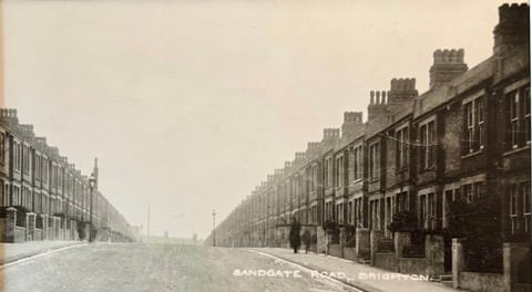 A vintage sepia photograph captioned 'Sandgate Road, Brighton' of a long Victorian terraced street receding into the distance, with a lone figure on the empty road.