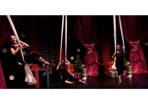 A three-part sequence of a performer on white aerial silks on a red-curtained Christmas stage — suspended in the silks, hanging low beside wrapped presents and a tree, then standing and smiling.
